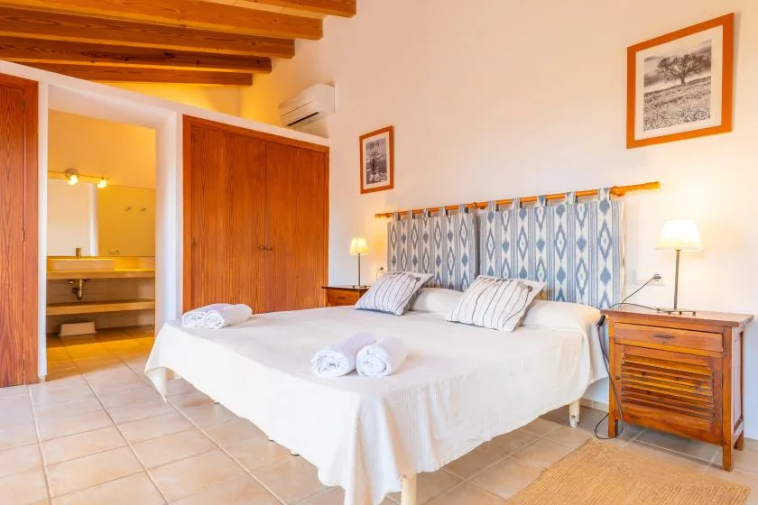 A bedroom with a large bed, patterned curtains, and wooden ceiling beams.