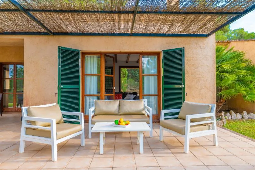 A shaded outdoor seating area sits in front of an open doorway.