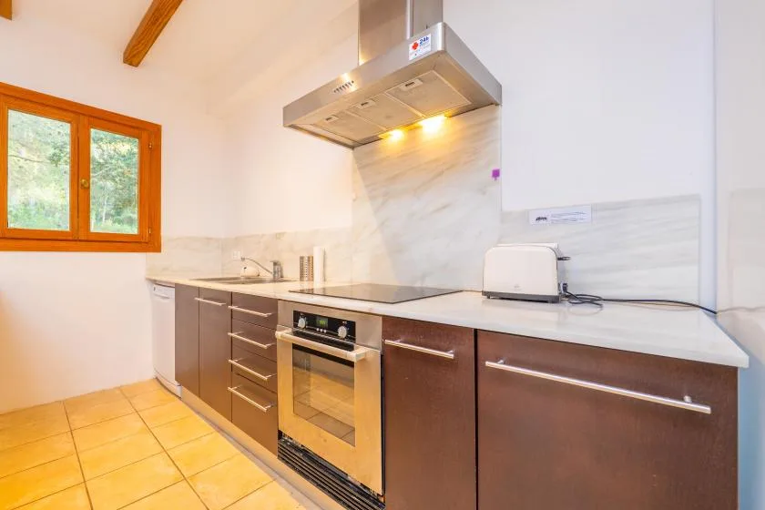 A kitchen with a countertop, oven, and window.