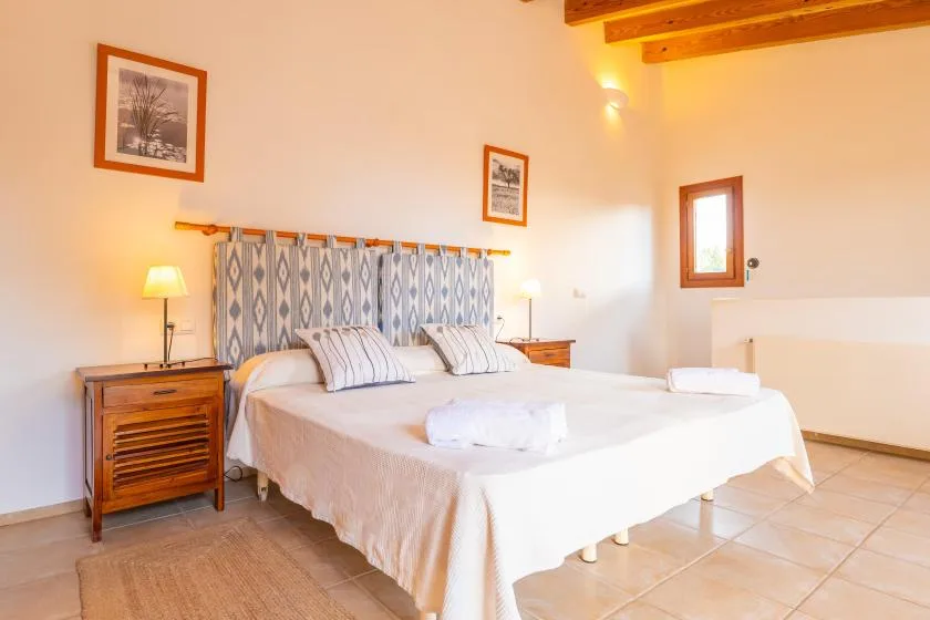 A bedroom with a bed, bedside tables, and framed wall art.