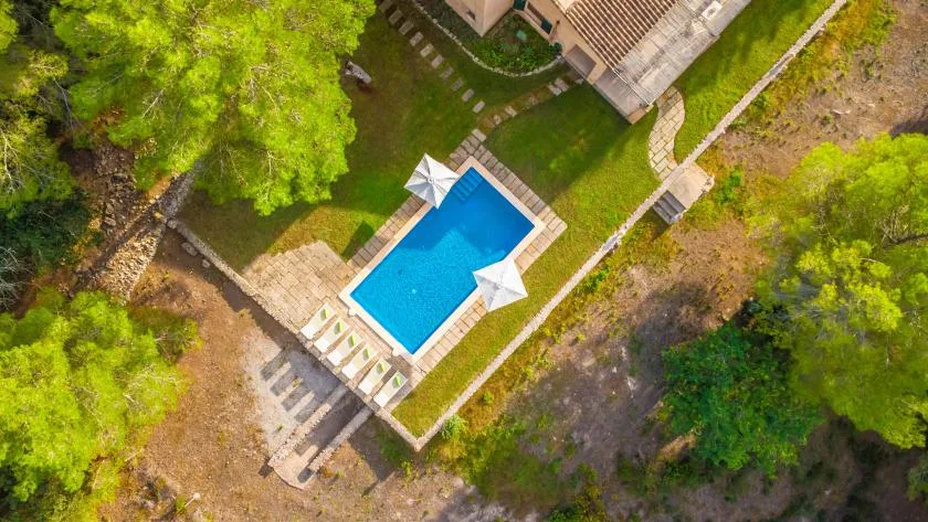 An aerial view shows a swimming pool beside a landscaped lawn.