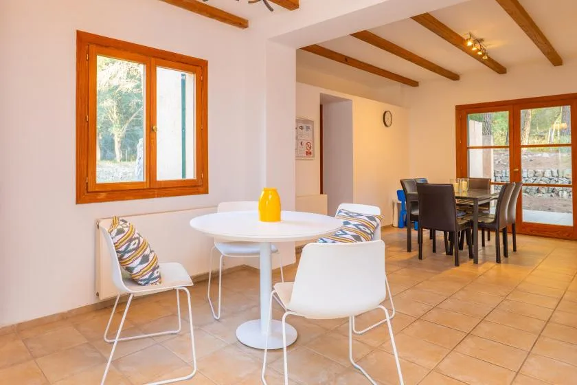 A bright dining area with a round table and chairs beside large windows.