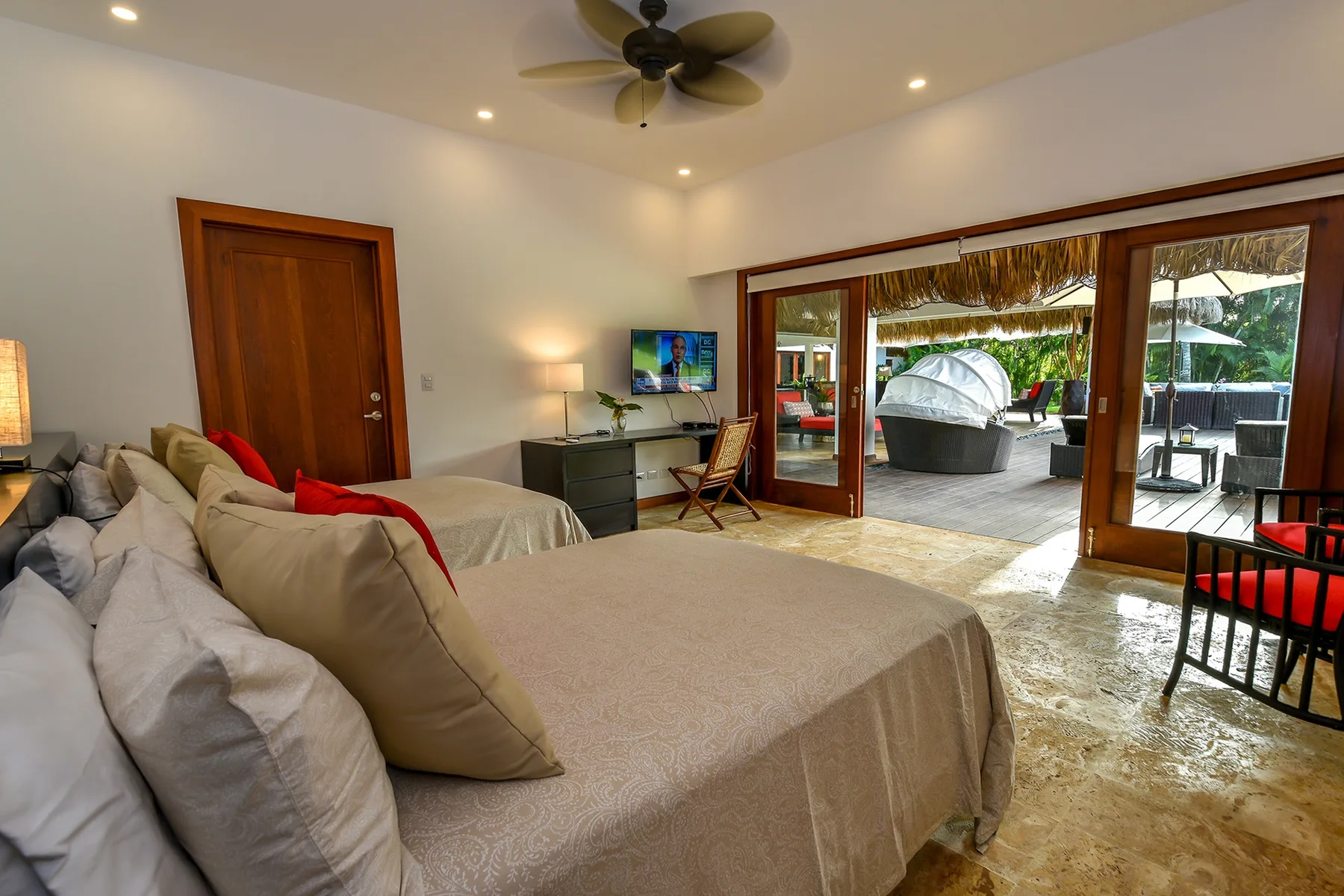 A bedroom with beds, a desk, and wide glass doors opening to a patio.