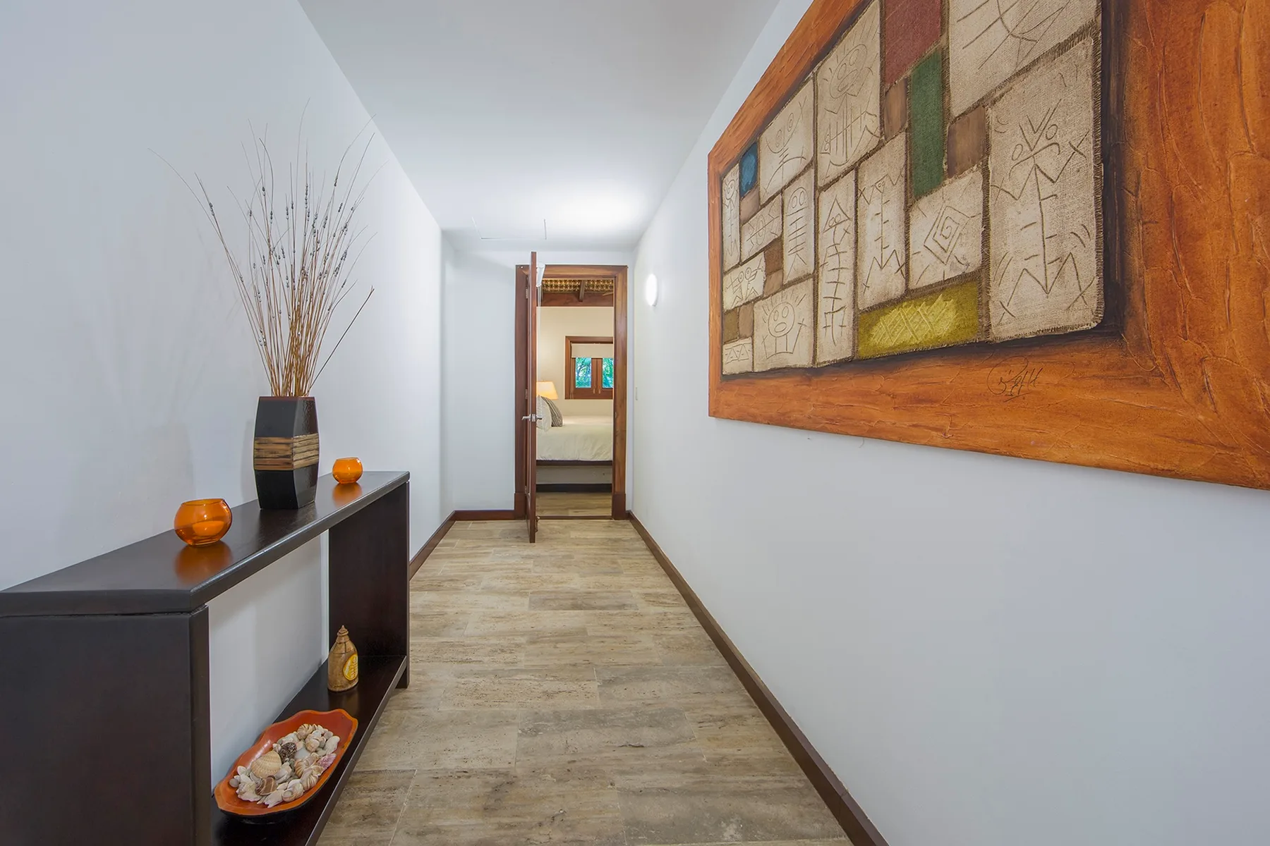 A narrow hallway with a dark console table and framed wall art.