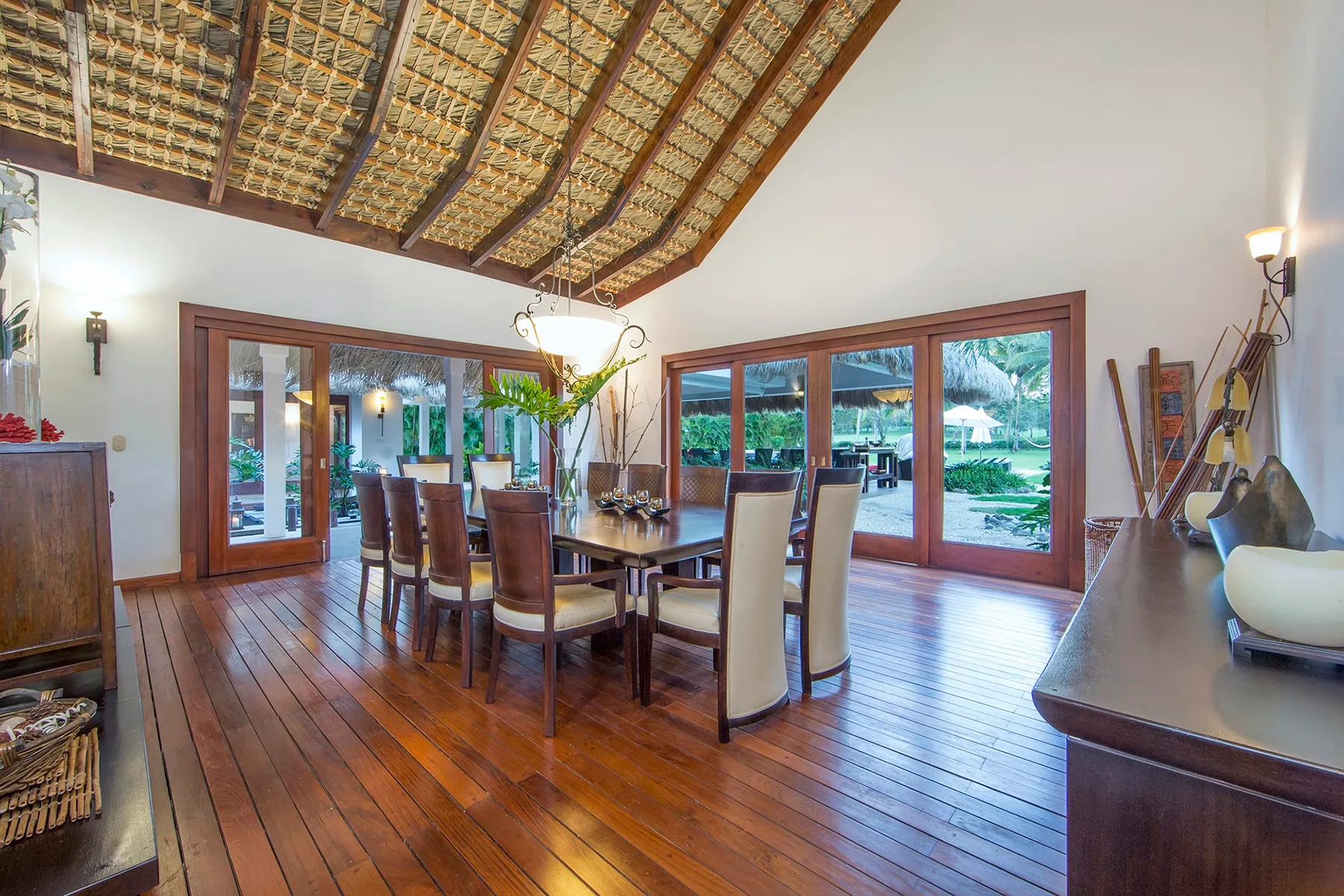 A dining room with a long wooden table beneath a high timber ceiling.