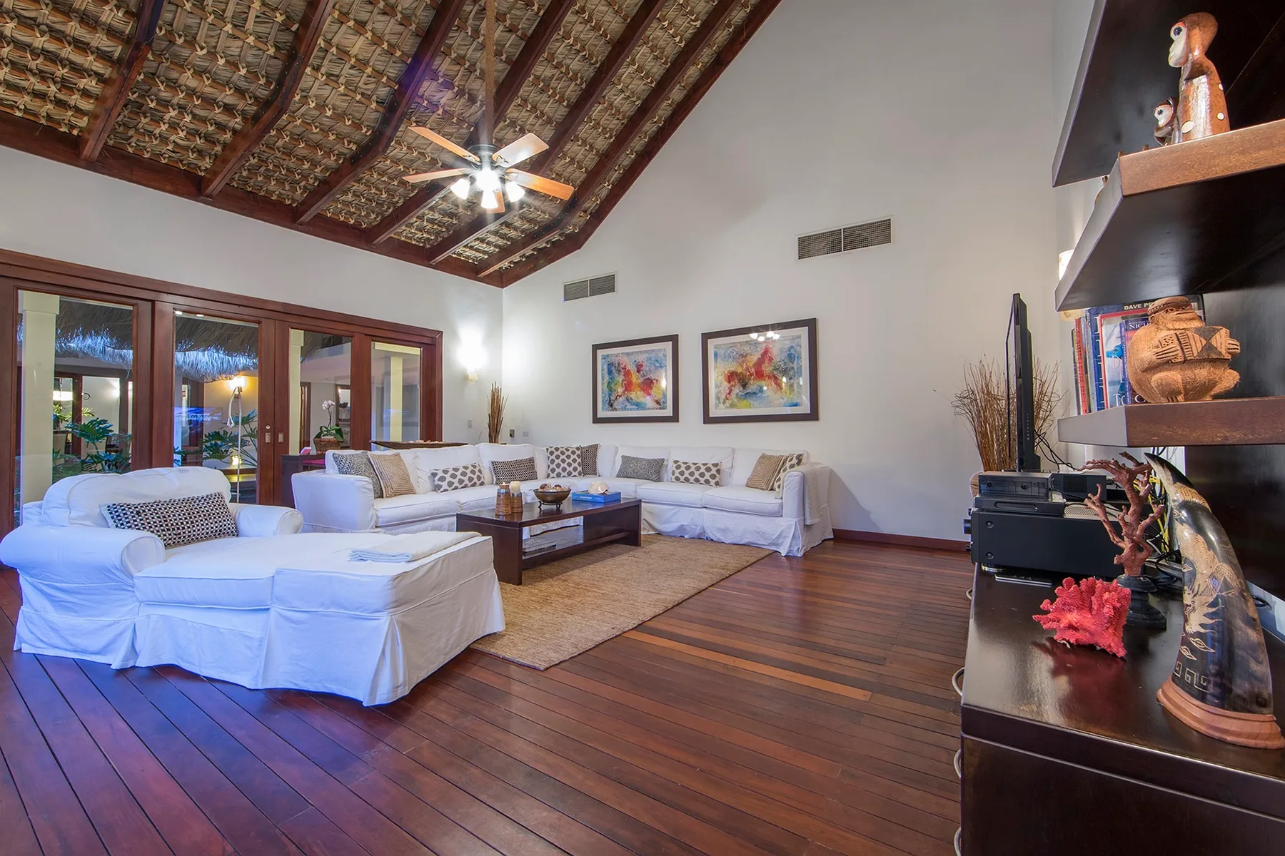 A living room with white seating, a wooden coffee table, and exposed ceiling beams.