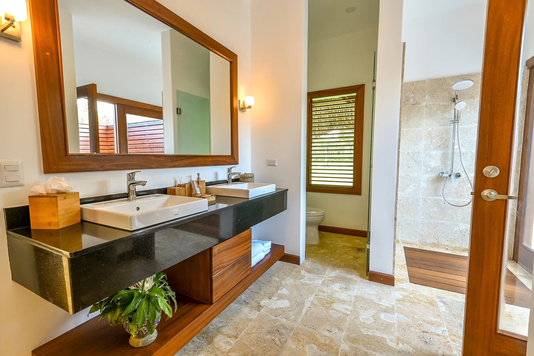 A bathroom with a long vanity and an open shower area.