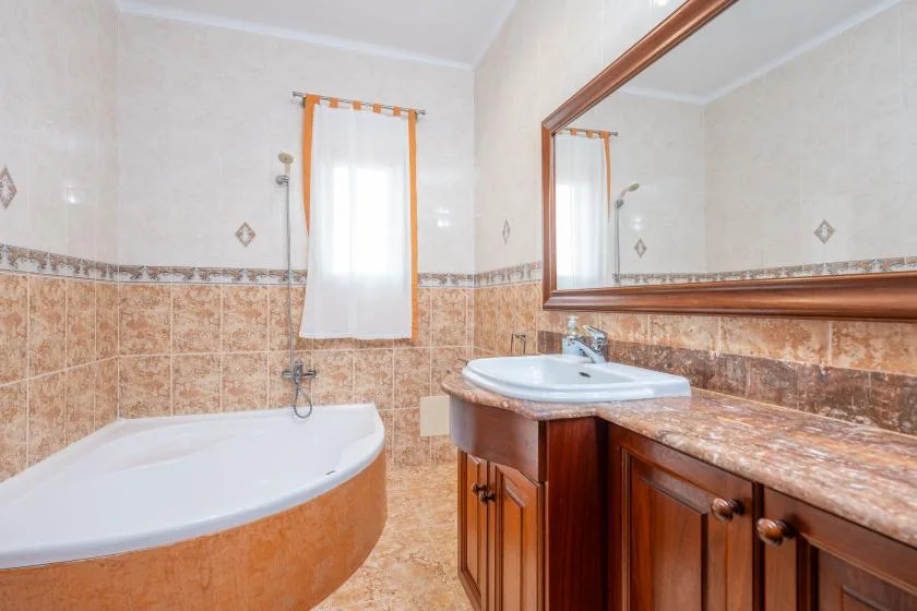 A bathroom with a bathtub, a sink, and a large wall mirror.