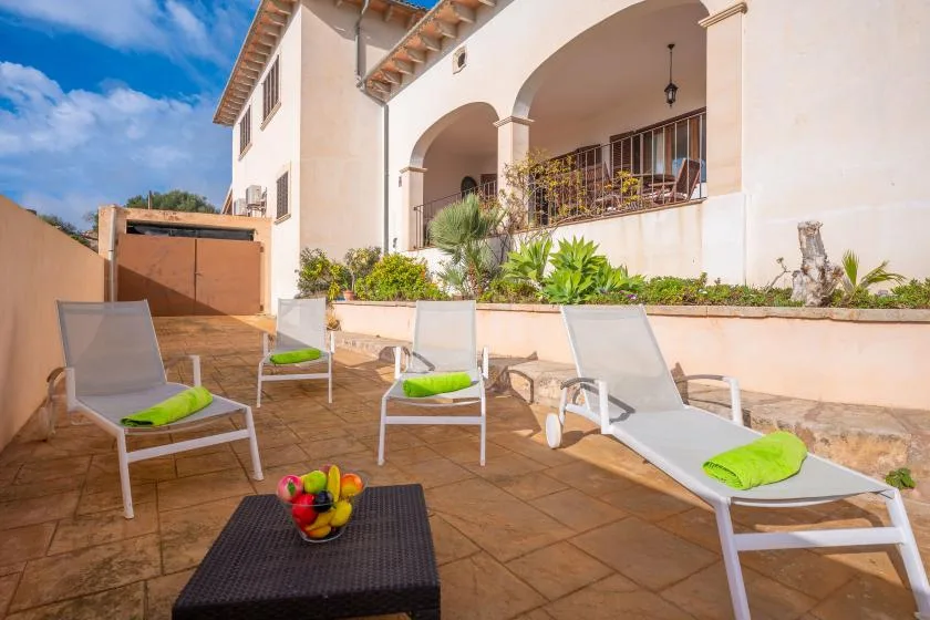 A sunlit patio with reclining seating and a covered veranda.