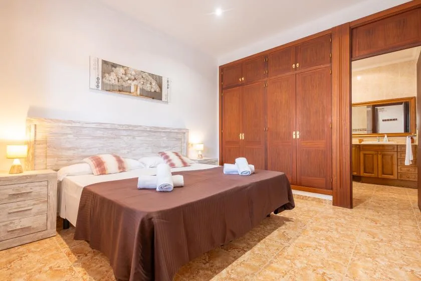 A bedroom with two beds, bedside tables, and a large wooden wardrobe.