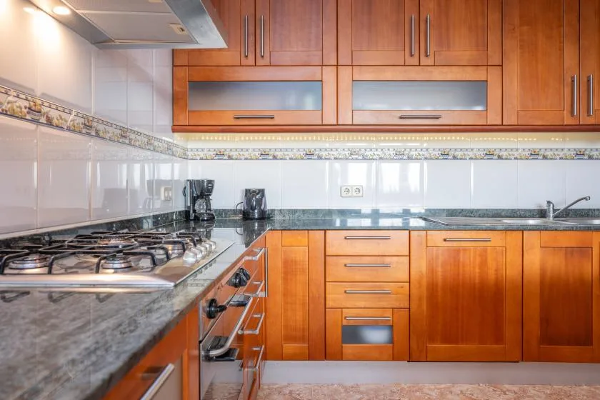 A kitchen with wooden cabinets, a stovetop, and a countertop.