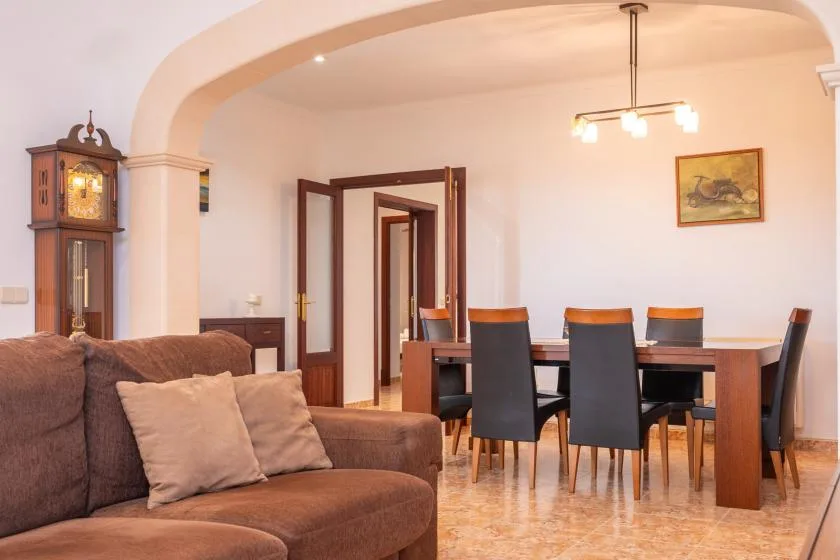 A living and dining area with seating, a dining table, and a tall clock.