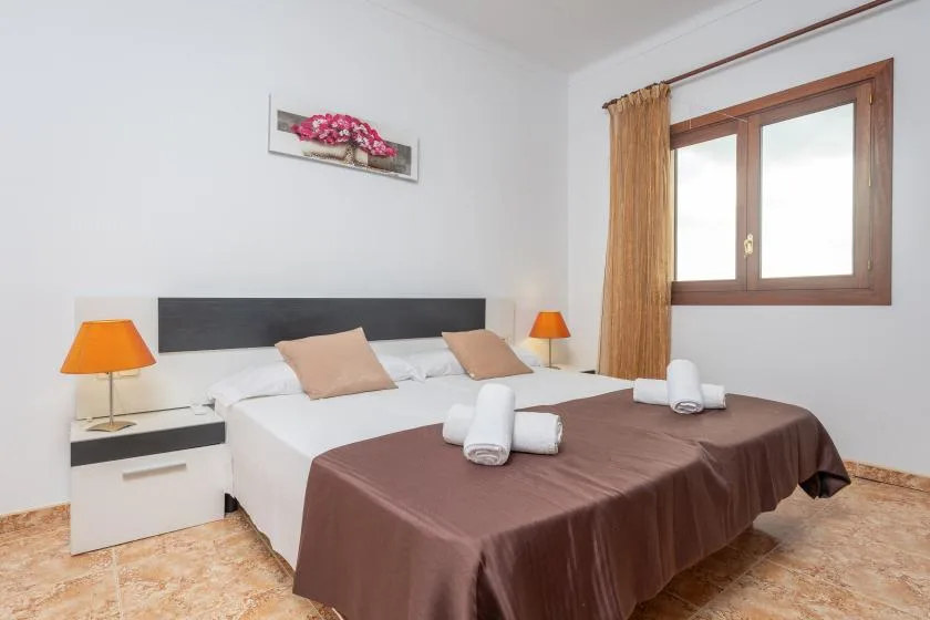 A bedroom with a double bed, bedside tables, and a window.