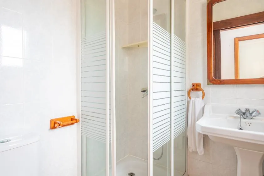 A bathroom with a glass shower enclosure and a sink beneath a mirror.