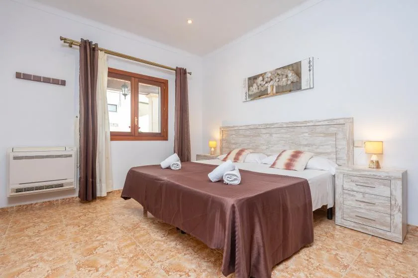 A bedroom with a large bed, brown bedspread, and a window with curtains.
