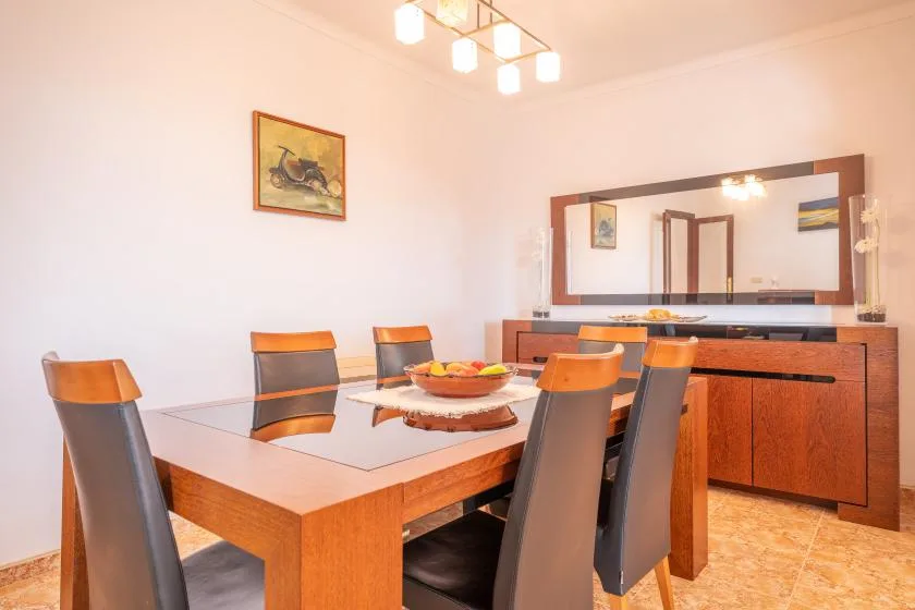 A dining room with a wooden table, upholstered seating, and a large wall mirror.