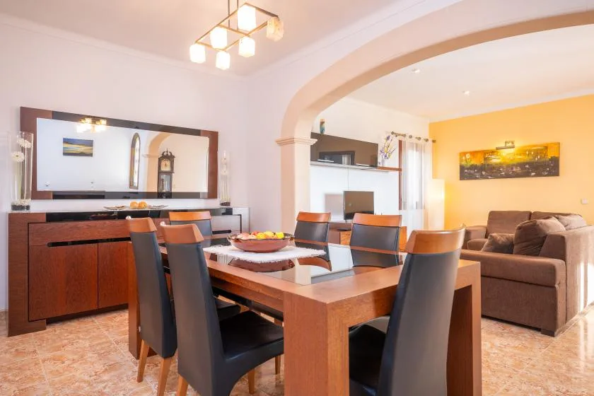 A dining area with a wooden table and seating opens onto a living room.