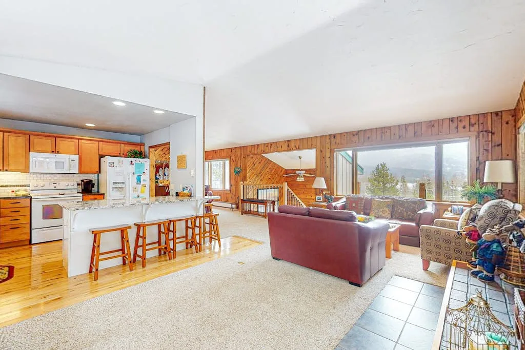 Sala de estar y cocina de planta abierta con una barra y asientos.
