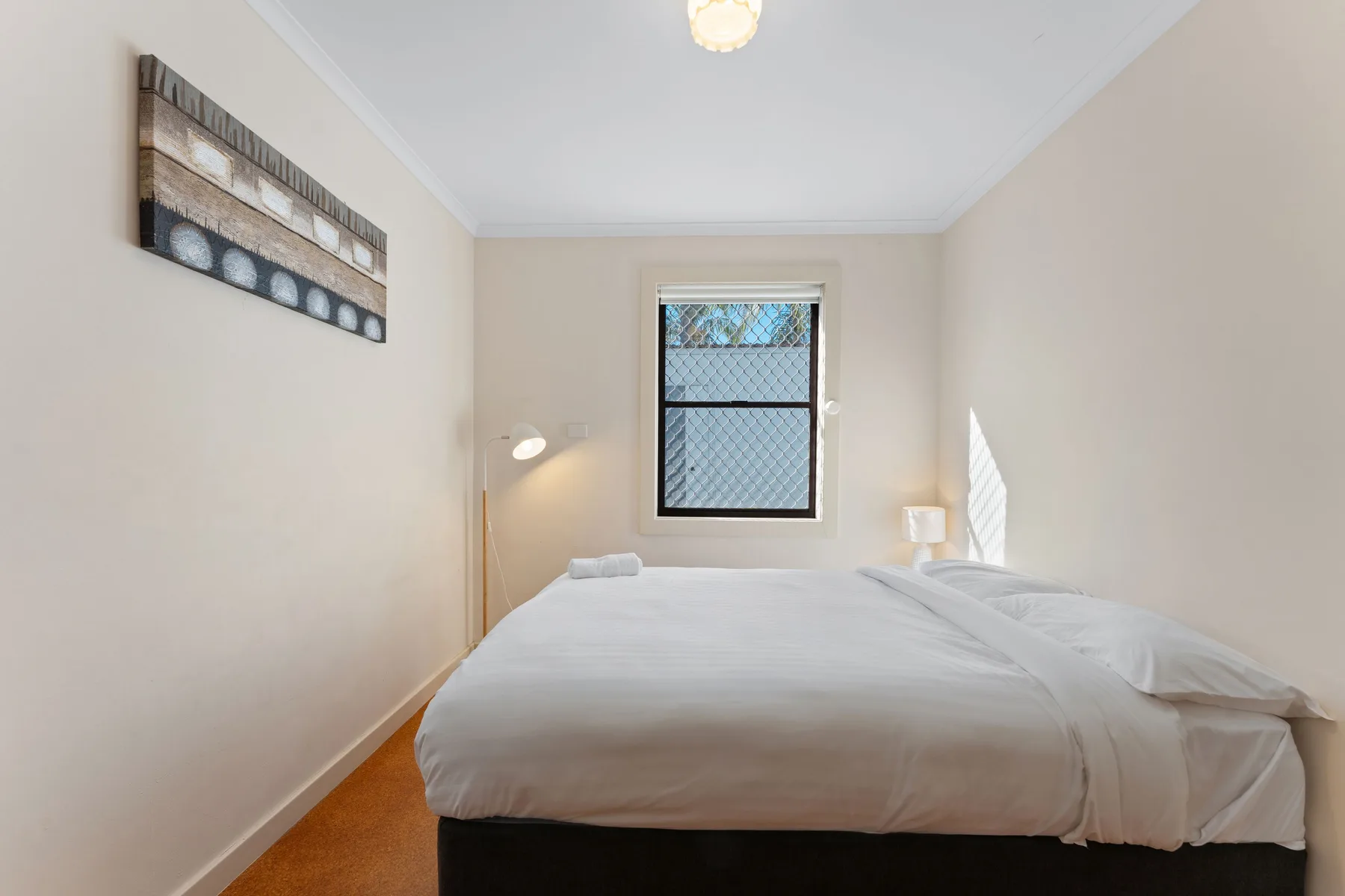A bright bedroom with a neatly made bed and a window.