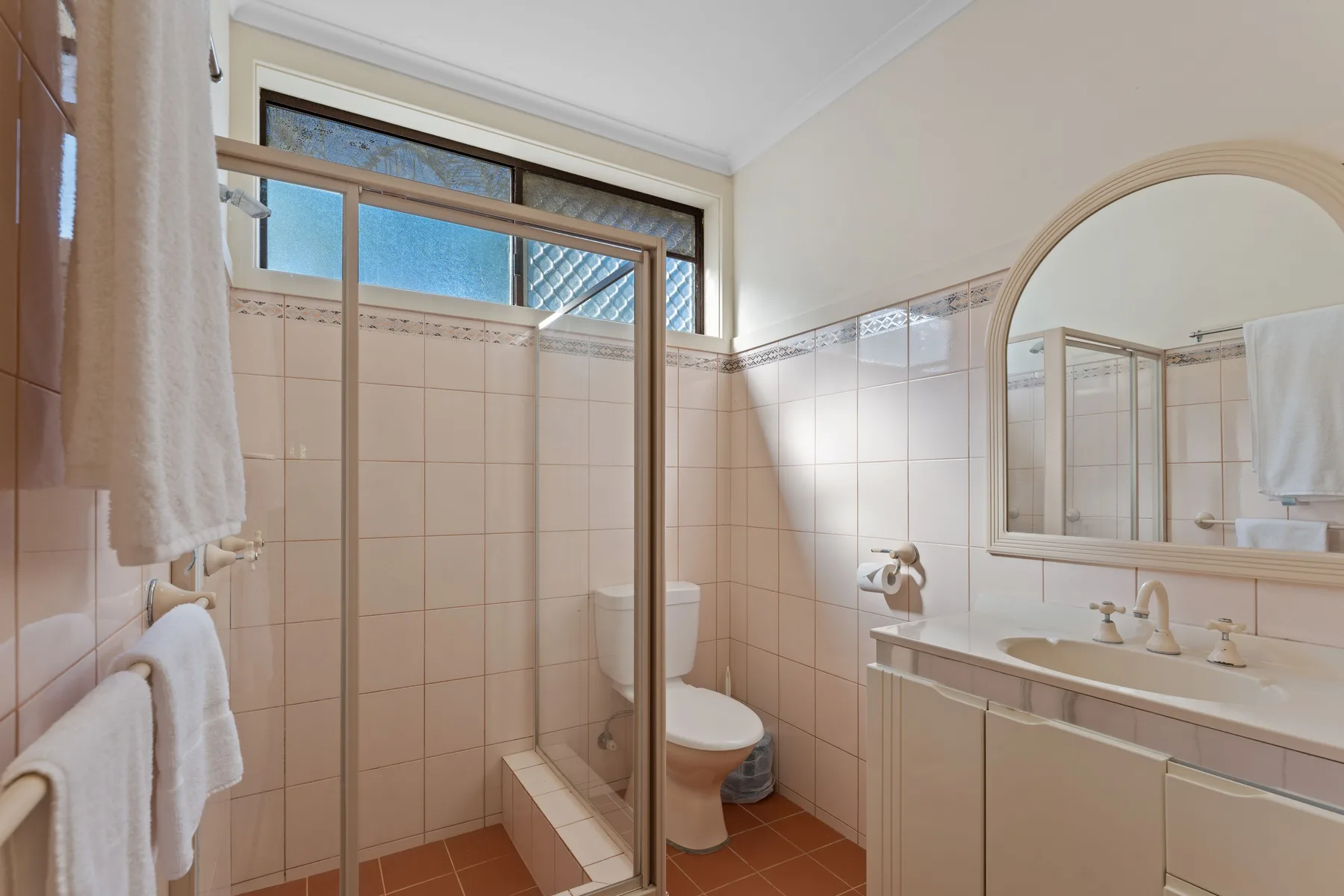 A tiled bathroom with a shower, toilet, and sink.