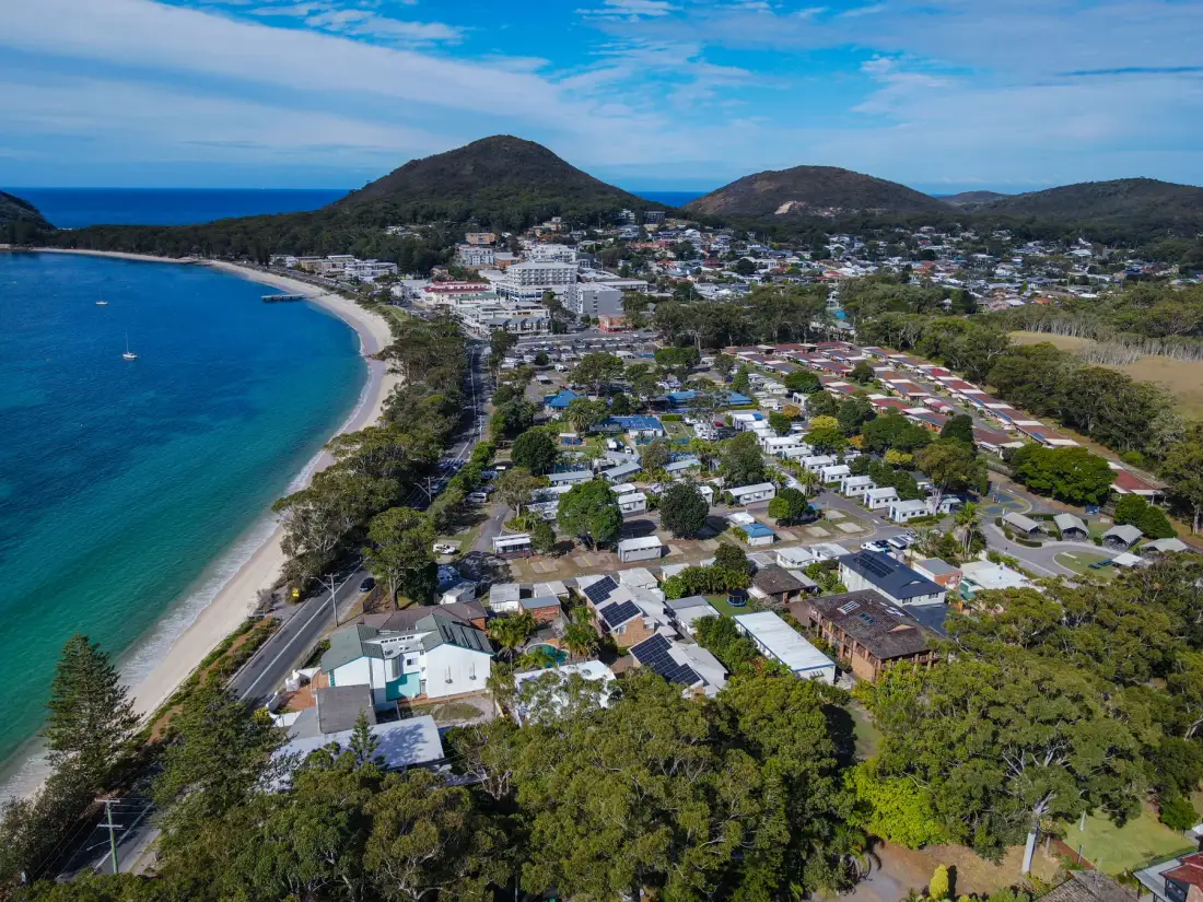 Aerial view of a coastal town beside a curved beach and turquoise water.