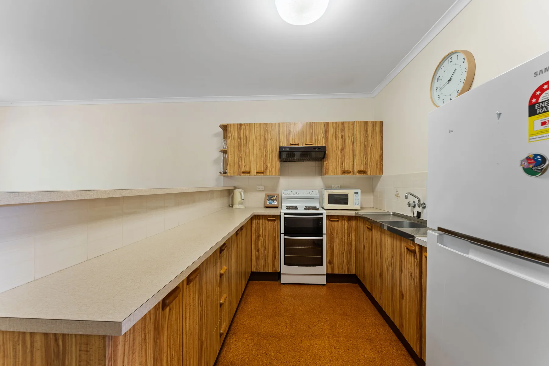 A kitchen with wooden cabinets, a long countertop, and cooking appliances.