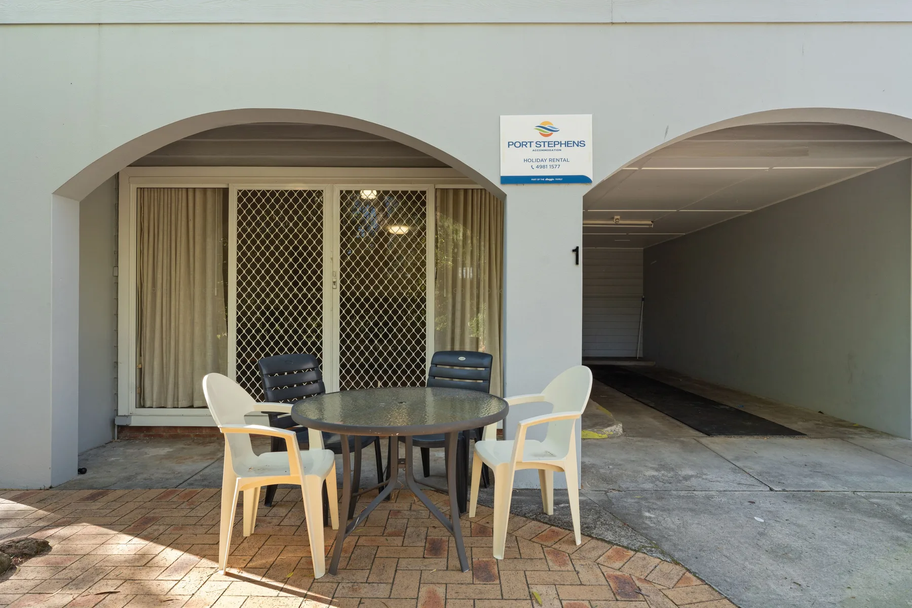 A covered entrance area with outdoor seating beside a driveway.