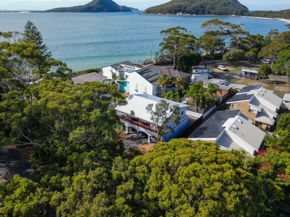Aerial view of buildings among trees beside a bay.
