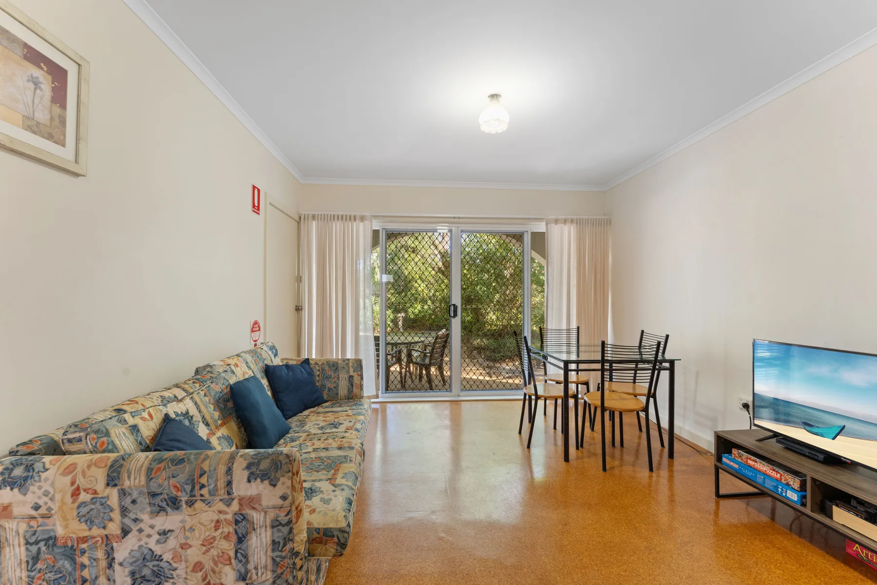 A living and dining area with seating, a table, and sliding glass doors.