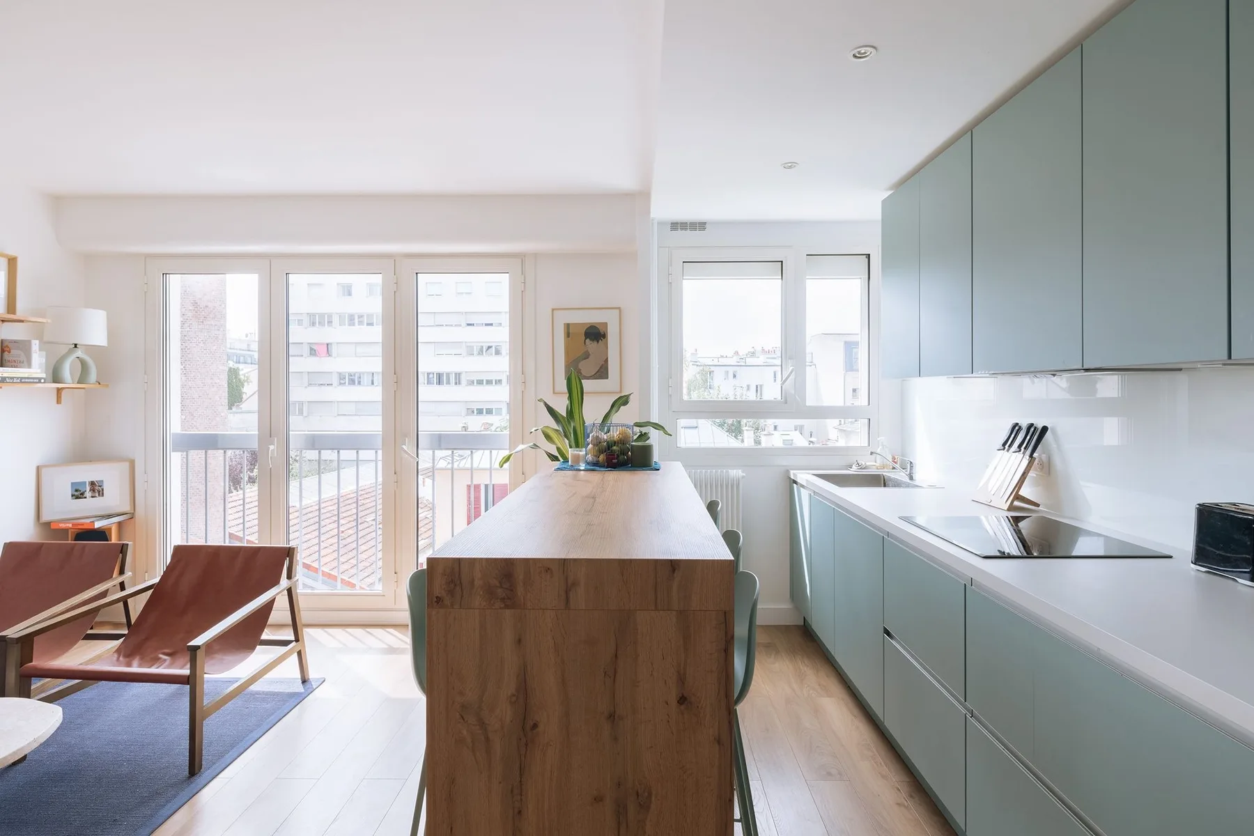 A bright kitchen with pale cabinets, a long island, and large windows.