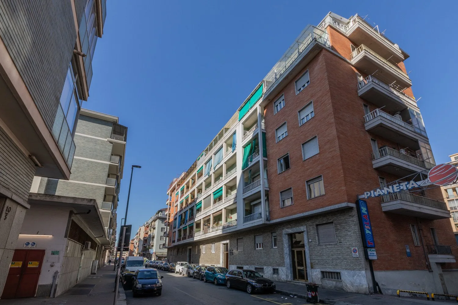 A city street lined with apartment buildings under a clear blue sky.