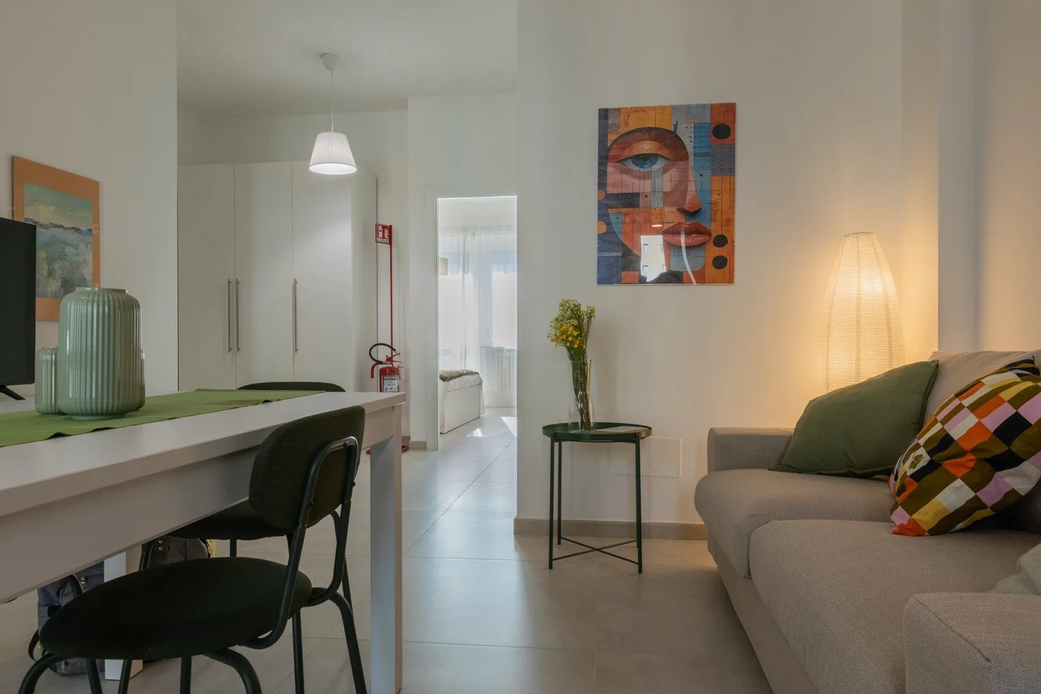 A living room with a sofa, a counter with seating, and colorful wall art.
