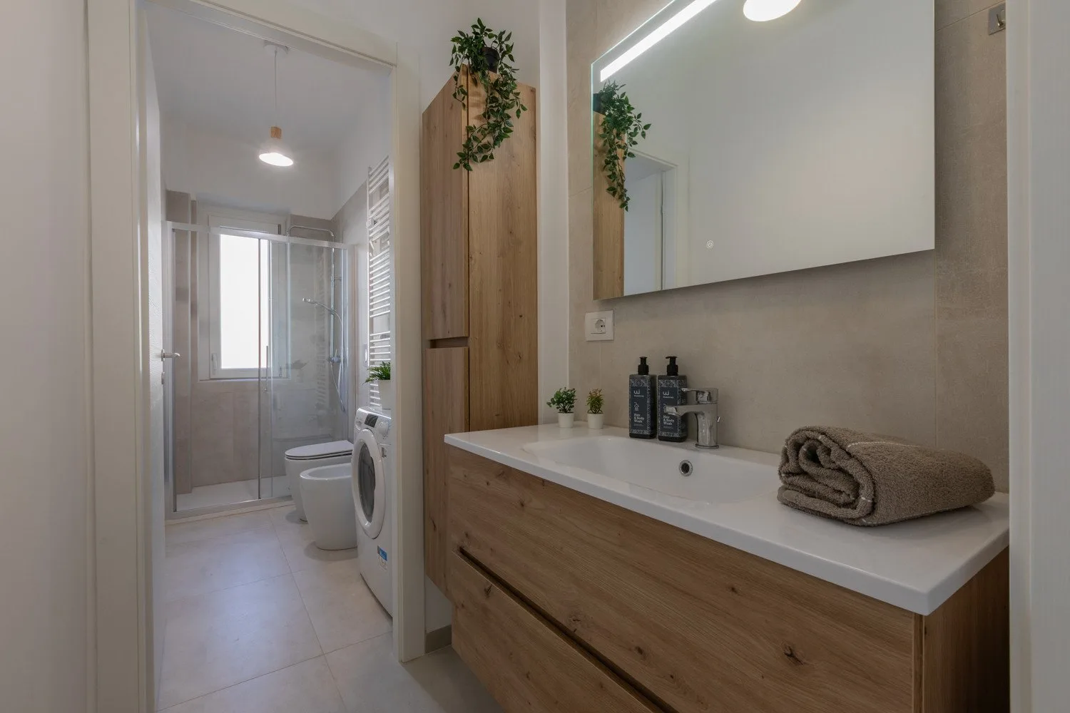 A bathroom with a long sink counter and a shower area.