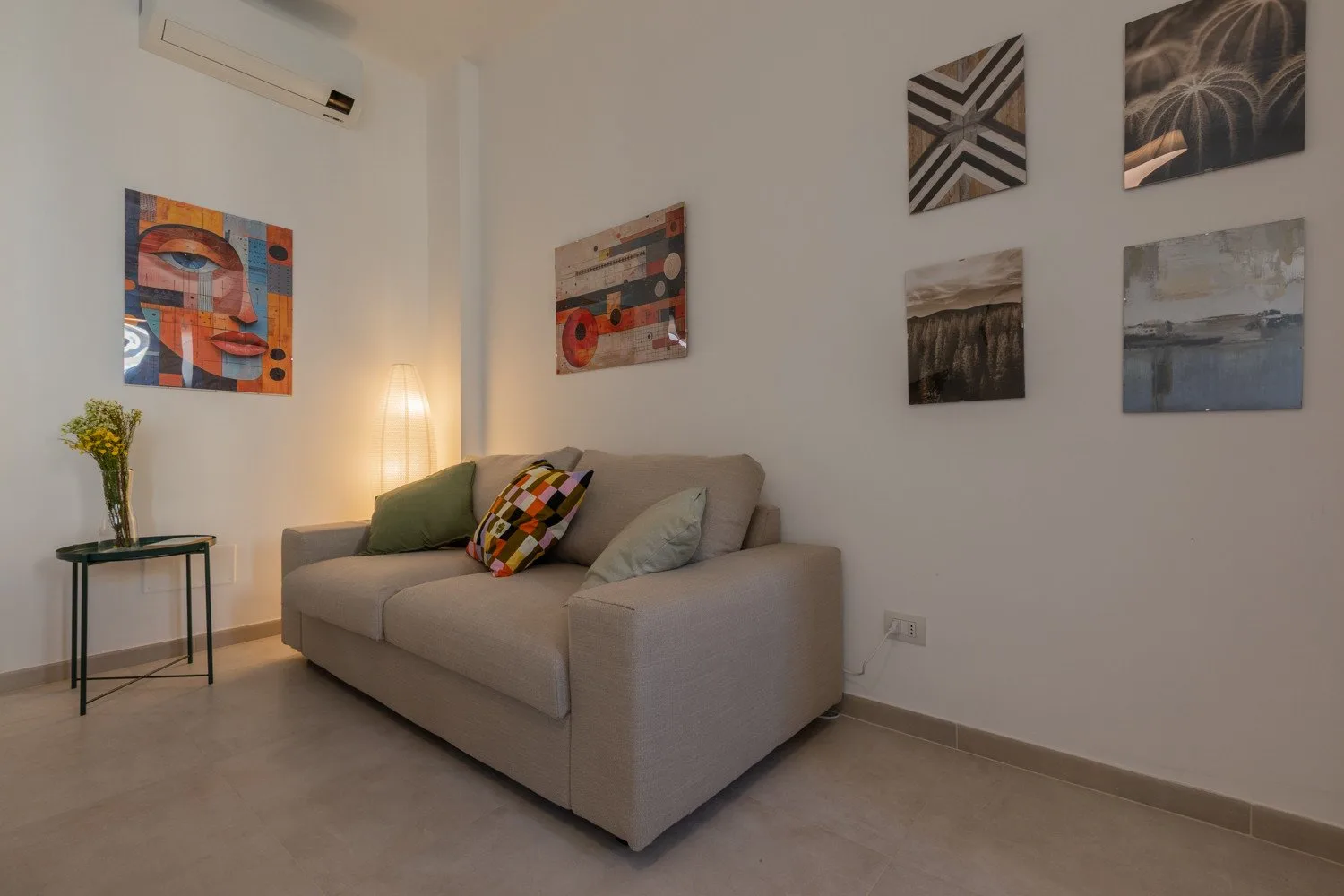 A living room with a gray sofa, colorful cushions, and abstract wall art.