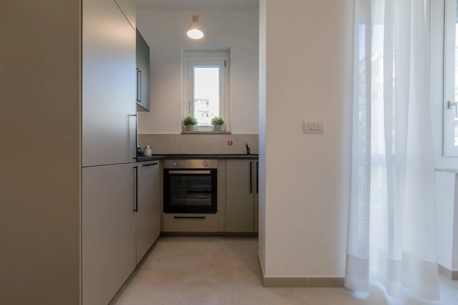 A compact kitchen with built-in cabinetry, an oven, and a window.