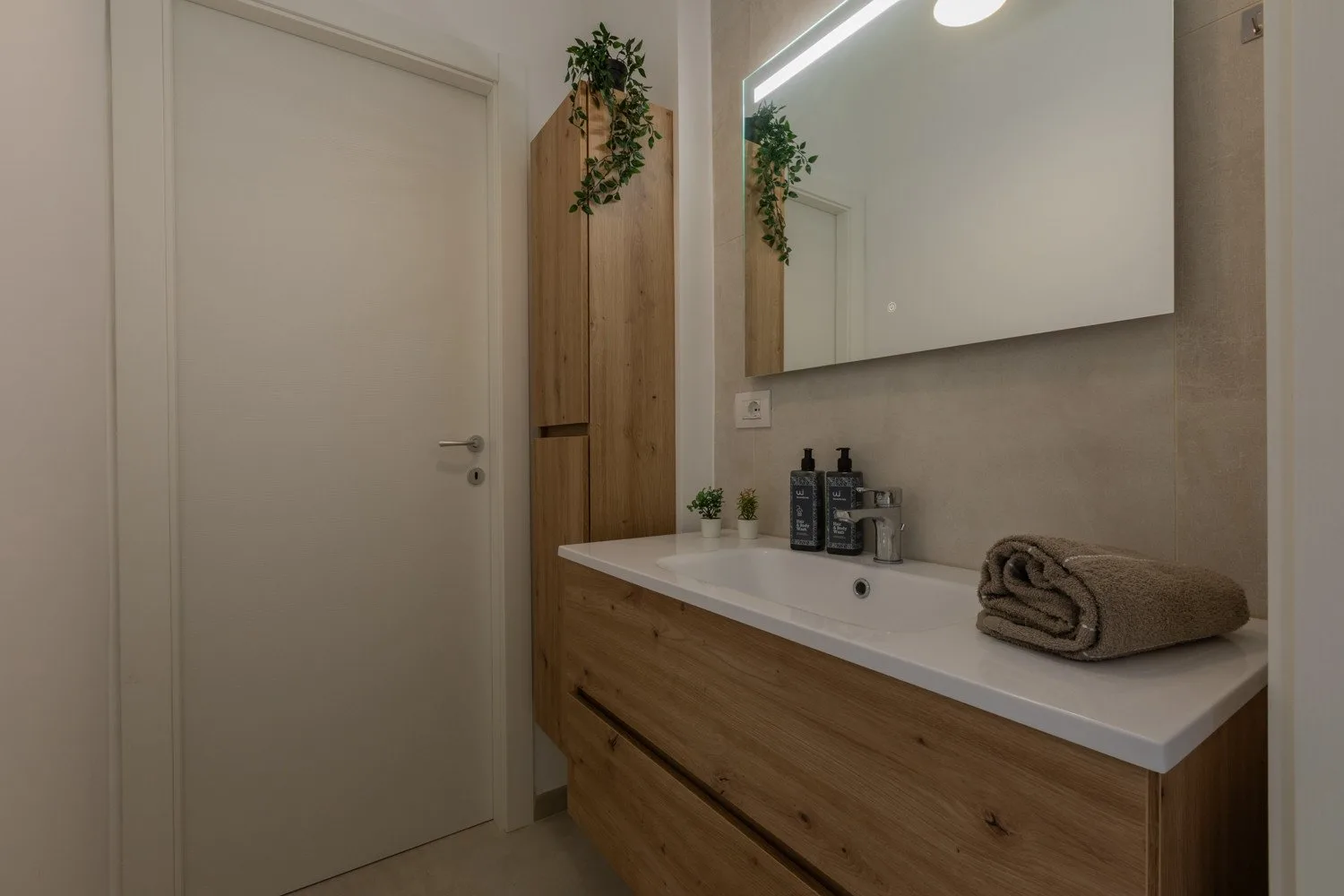 A bathroom vanity with a mirror, toiletries, and a folded towel.