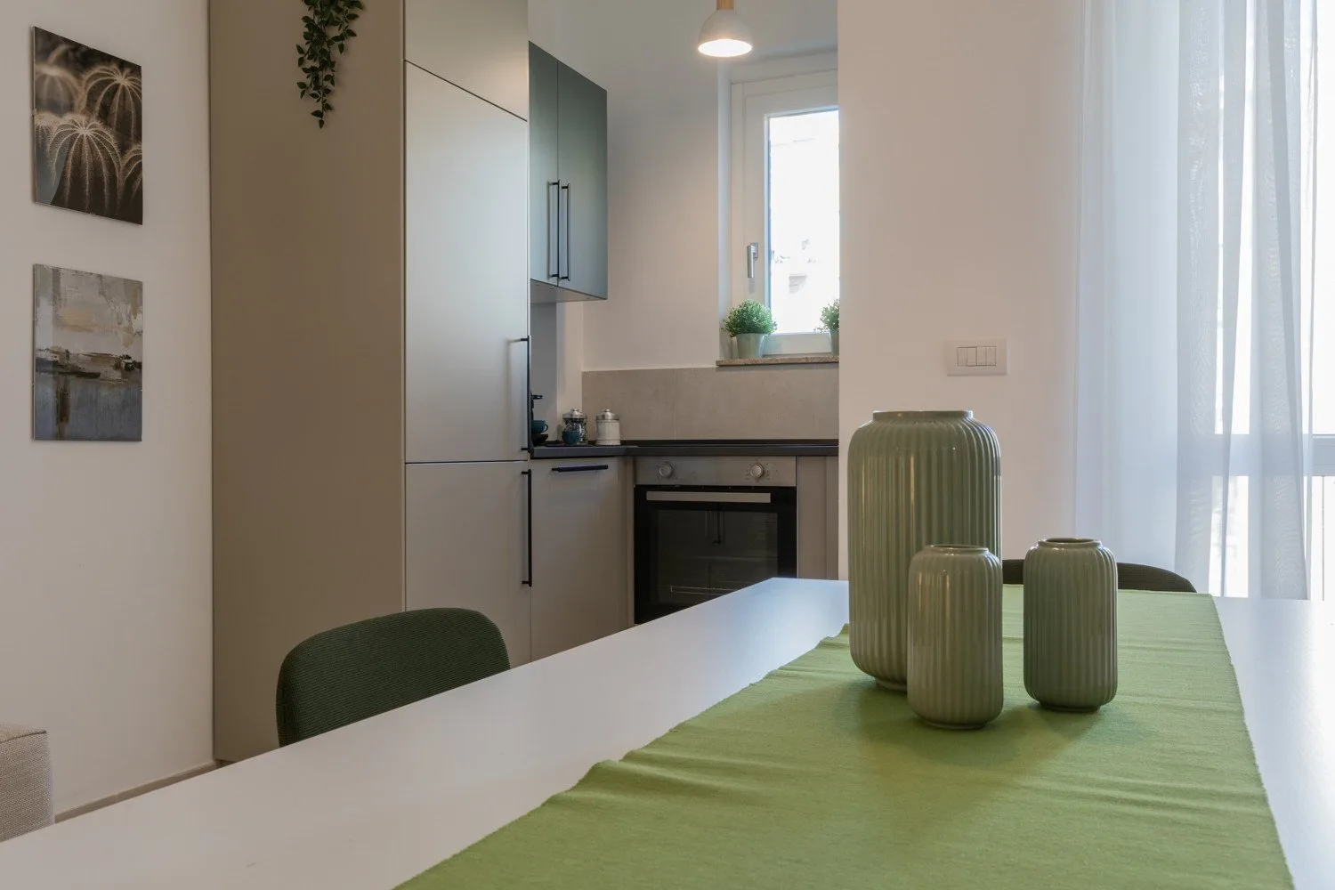 A dining table with green accents sits beside a compact kitchen.