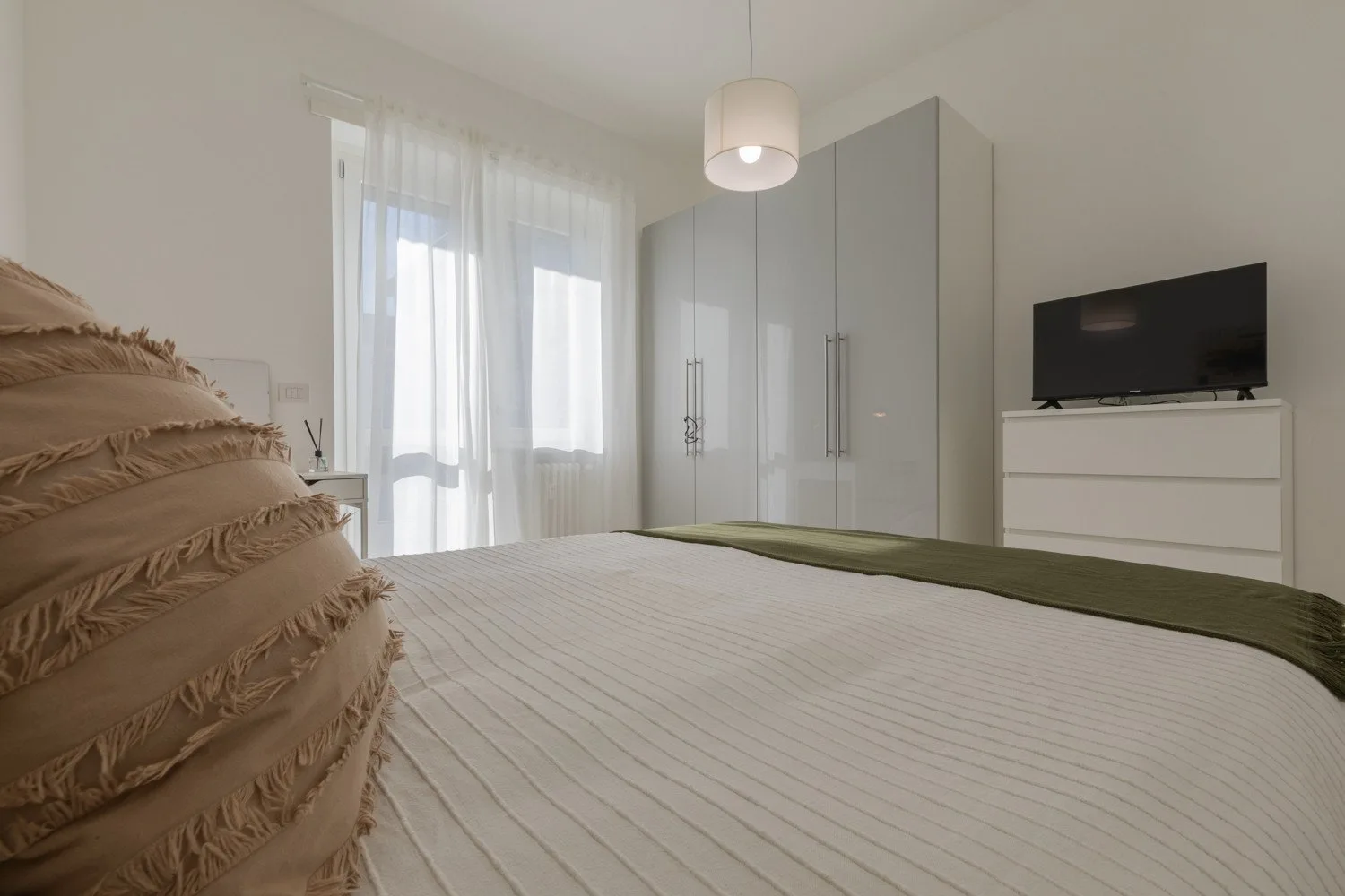 A bedroom with a bed, wardrobes, and a television on a dresser.