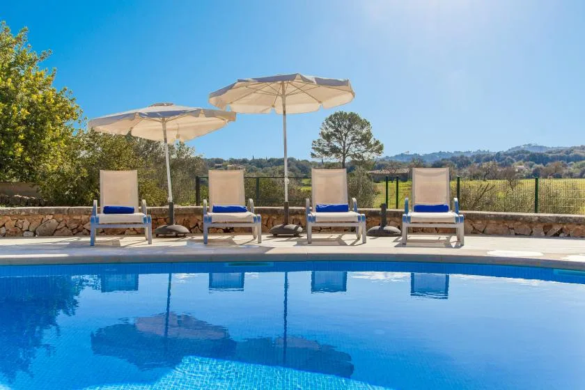 An outdoor swimming pool is lined with lounge seating and sun umbrellas.