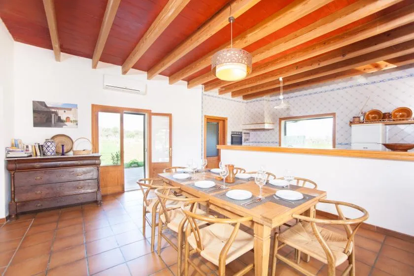A dining area with a wooden table and chairs beneath exposed ceiling beams.