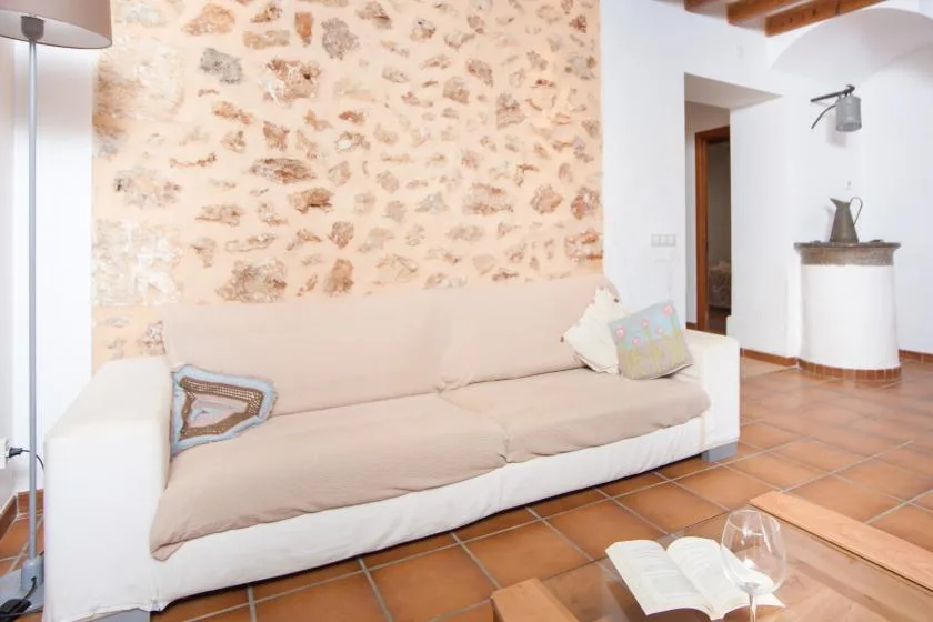 A living room with a pale sofa against a stone-patterned wall.