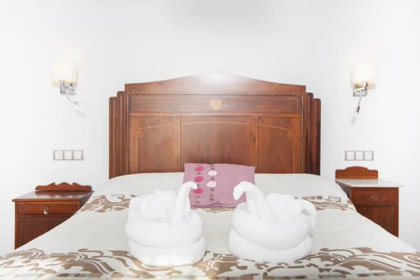 A bedroom with a carved wooden headboard and folded towels arranged on the bed.