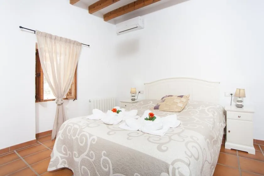 A bedroom with a patterned bedspread, bedside tables, and a curtained window.