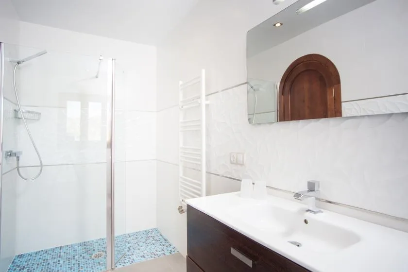 A bright bathroom with a glass shower and a white sink vanity.