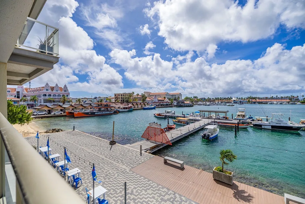Scenic waterfront property featuring a marina, colorful Caribbean architecture, and dramatic tropical skies, offering picturesque surroundings just steps from the harbor.