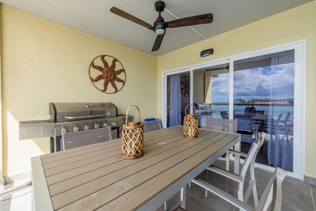 Your private balcony overlooks the water, featuring a full grill and dining table with ceiling fan—perfect for sunset dinners and morning coffee with coastal views.