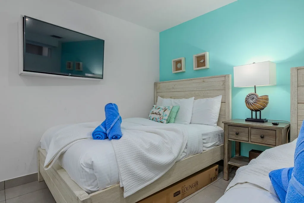 Sink into crisp white linens and drift off under the calming turquoise accent wall. Your coastal-themed bedroom features a wall-mounted TV, nautical décor, and soft lighting for restful evenings.