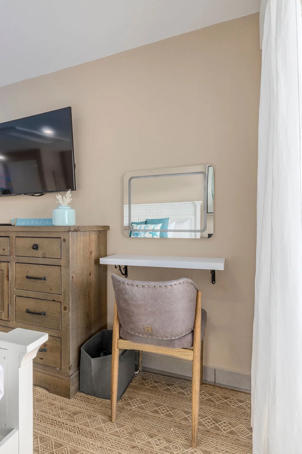A cozy corner awaits with a small vanity and chair, perfect for getting ready each morning, plus a flat-screen TV and charming rustic dresser for your belongings.