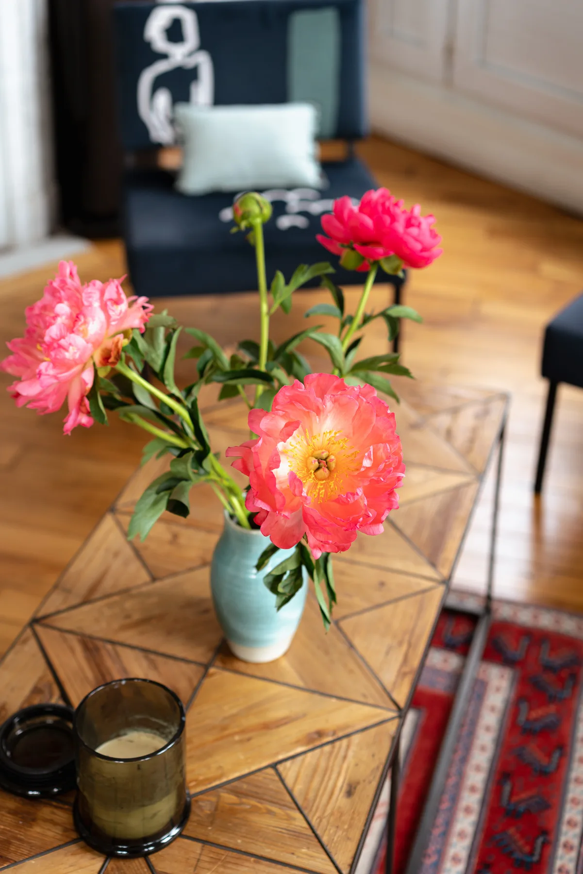 A vase of pink flowers sits on a wooden coffee table in a living room.