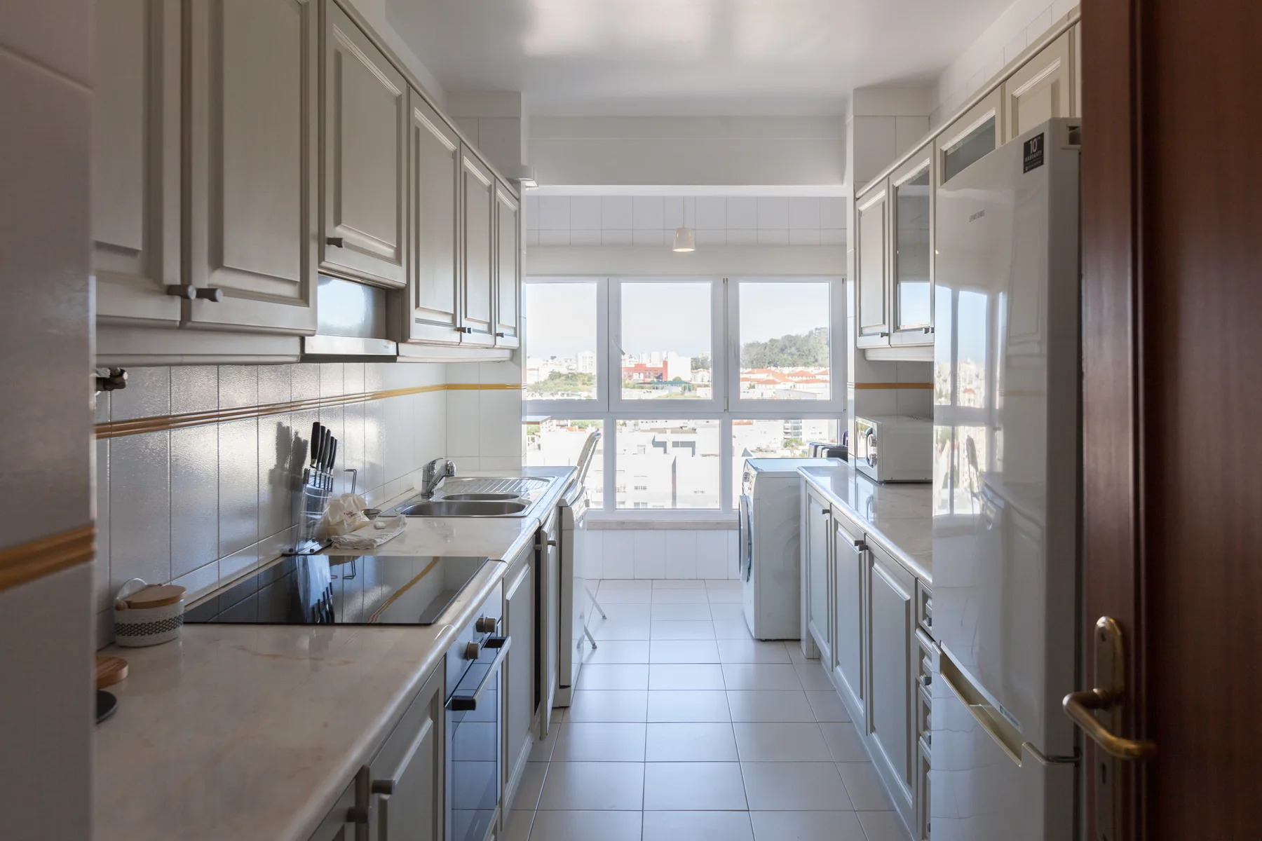 Una cocina estrecha con encimeras a ambos lados y una ventana grande al fondo.